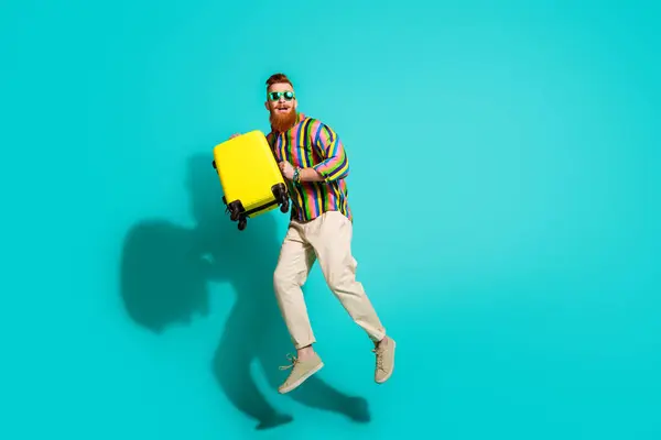 stock image Full body size photo of crazy man in striped shirt hipster bring baggage shocked look at airport schedule isolated on cyan color background.