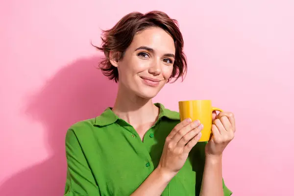 可爱的年轻女士拿着咖啡杯的照片肖像 穿着时髦的绿色衣服 背景是粉色的 — 图库照片