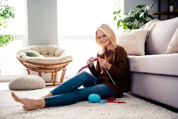 Photo of adorable calm kind woman pensioner sitting on soft knitting scarf white day light weekend indoors.