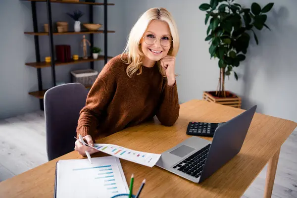 照片上的金发成熟女士微笑着在工作场所台式机增长营销经理分析图表在总部办公室 — 图库照片