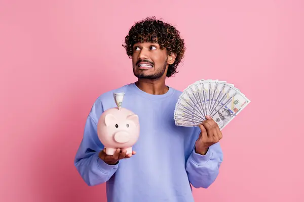 Photo of worried nervous man wear trendy blue clothes hold piggy box dollars look empty space oops isolated on pink color background.