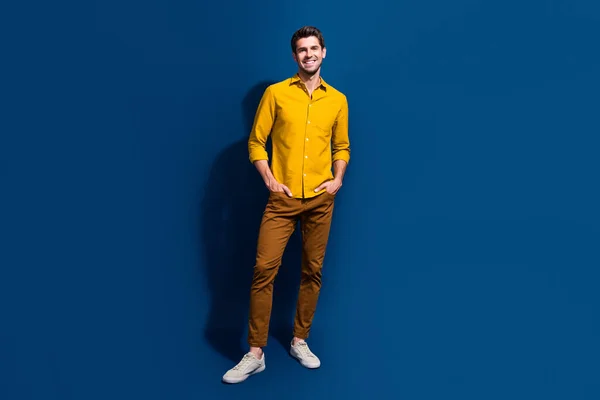 ダークブルーの背景に隔離されたスタイリッシュな黄色の服を着た魅力的な若者の手のポケットのフルサイズの写真 — ストック写真