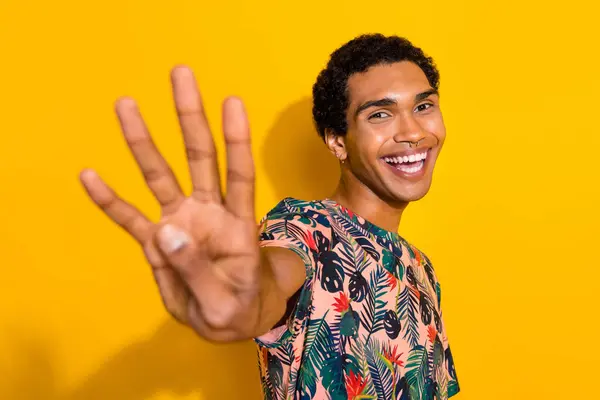 Photo of funky cheerful man wear print t-shirt showing you four fingers isolated yellow color background.