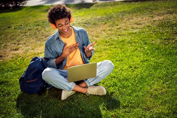 Stock image Photo of positive cheerful guy wear denim jacket earphones communicating modern gadget outside urban city street.