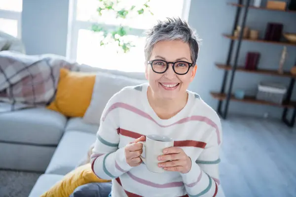Photo of positive good mood woman dressed striped sweater eyewear enjoying tasty beverage indoors house home room.