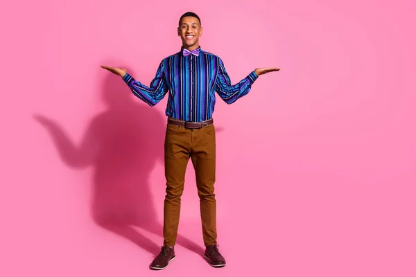 陽気なクールな男の完全な長さの写真は 空のスペースを比較する腕のスケールを示すストライプのシャツを着用します ピンク色の背景 — ストック写真