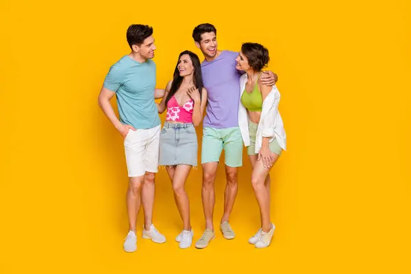 Full body photo of four people best buddies hug embrace have fun chat isolated over vivid color background.