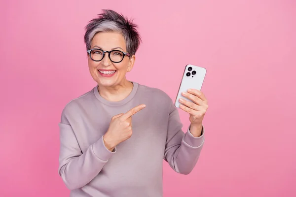 快乐有趣的退休妇女展示小玩意的照片推荐购买基于粉色背景的现代设备 — 图库照片