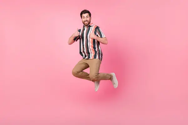 成年男子跳蹦床全体长照片显示双大拇指在粉色背景下有很好的分度 — 图库照片