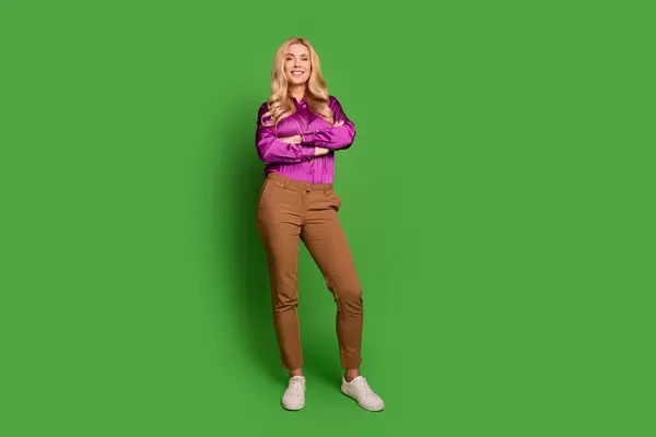 自信を持って陽気な女性の完全な長さの写真 ヴァイオレットのシャツの腕を着用 空のスペースを隔離された緑色の背景 — ストック写真