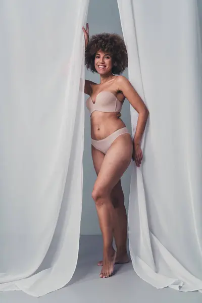Unretouched photo of body positive girl stand near white curtains welcome invite to cosmetology salon.