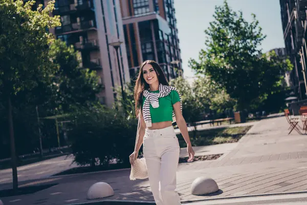 Photo of positive shiny young lady brunette hair model wear trendy casual outfit enjoying summer vibes walking streets outdoors city.