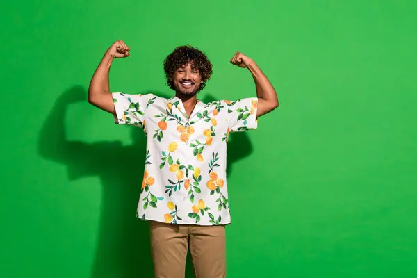 漂亮的年轻男性照片肖像显示肌肉拳头身穿时髦的柑橘印花套装 与绿色背景隔离 — 图库照片