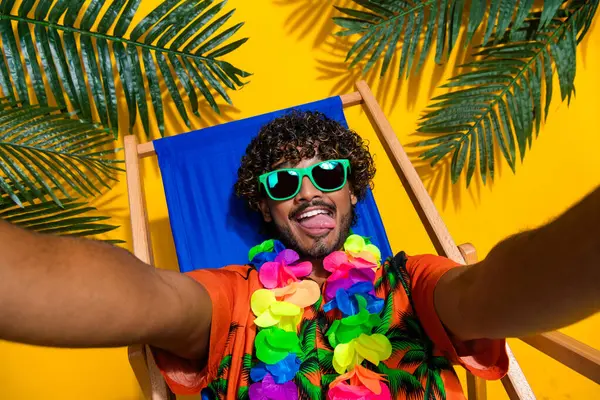 サングラスショーの舌でプリントシャツフラワーネックレスを着たファンキーな男の写真は 黄色の背景に隔離された休暇でセルフィーを作ります — ストック写真