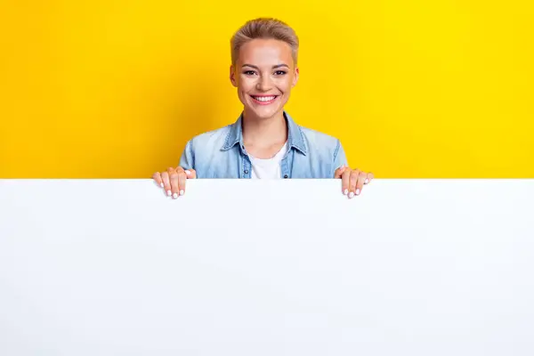 照片上的漂亮姑娘藏在白色空旷的空墙后面 穿着时髦的斜纹斜纹棉布衣服 背景是黄色的 — 图库照片
