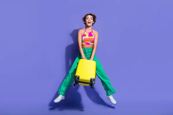 照片上快乐可爱的女孩穿着时髦的衣服跳着出境旅游季节性销售与紫色背景隔离 — 图库照片