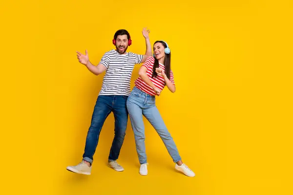 Full body photo of positive guy carefree girl enjoy new playlist dance empty space isolated on yellow color background.