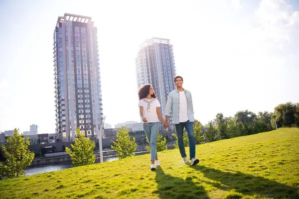 stock image Full body length photo of beautiful couple students soulmates holding hands together looking green backyard city buildings outdoors.