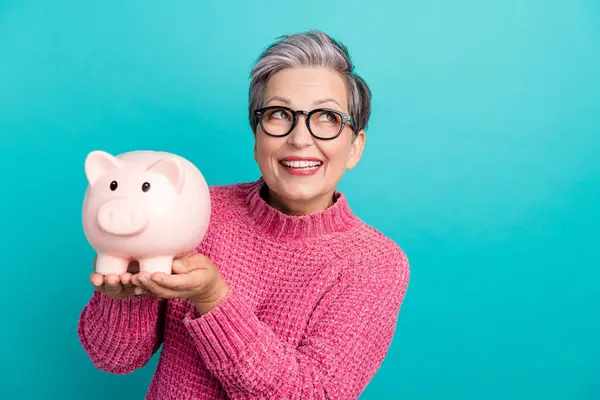 Portrait of smart person wear knit pullover in eyewear hold piggy box look at offer empty space isolated on turquoise color background.