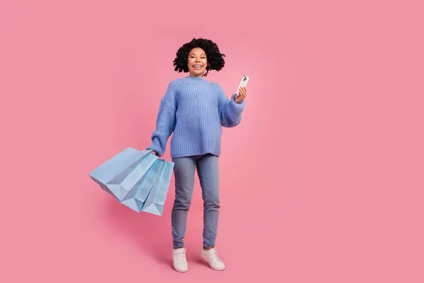かなり若い少女のフルサイズの写真 デバイス興奮する買い物客バッグ ピンク色の背景に隔離されたスタイリッシュな手がかり編まれた服 — ストック写真