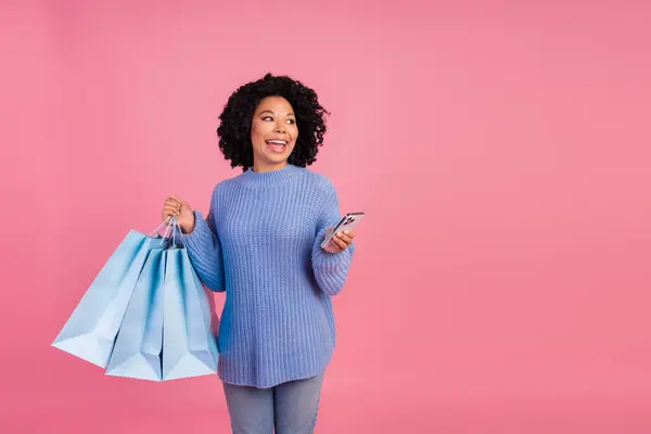 かなり若い少女の写真は デバイスのショッピングバッグは ピンク色の背景に隔離されたスタイリッシュな手がかり編まれた服を着た空のスペースに見えます — ストック写真