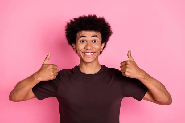 穿着棕色T恤 面带微笑 乐观的年轻人的画像 用粉色背景相隔离的双大拇指推荐姿势 — 图库照片