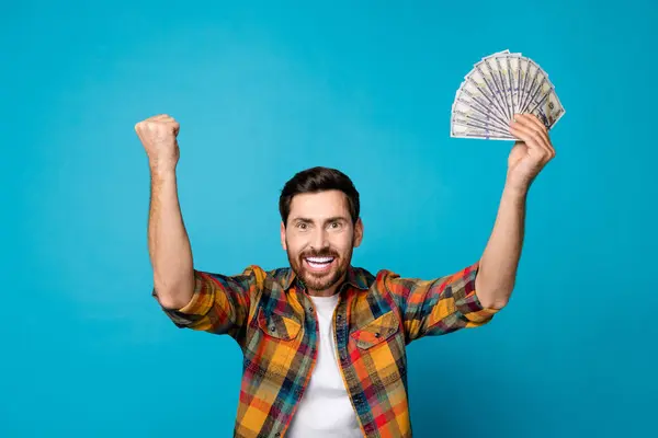 身穿时髦格子花衬衫的得意洋洋的男人举起一美元的拳头 在蓝色背景下被孤立起来的彩票大喊 — 图库照片