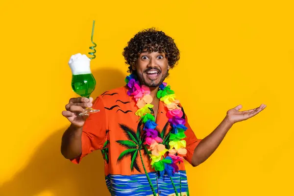 鮮やかな黄色の背景で隔離された手でエキゾチックな飲み物を保持するアフロヘアドレスの感銘を受けた満足した男性の写真 — ストック写真