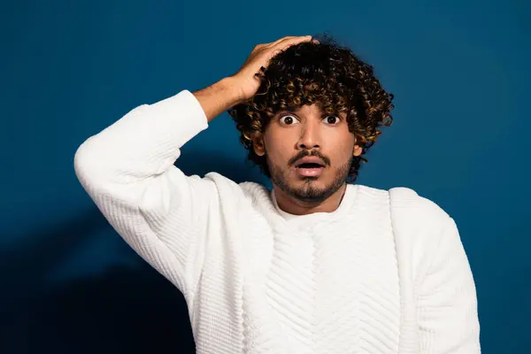 stock image Portrait of young guy saying oops hand touch head puzzled do not remember his account password isolated on dark blue color background.