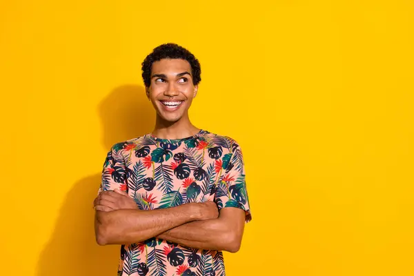 Photo of confident dreamy man wear print t-shirt arms crossed looking empty space isolated yellow color background.