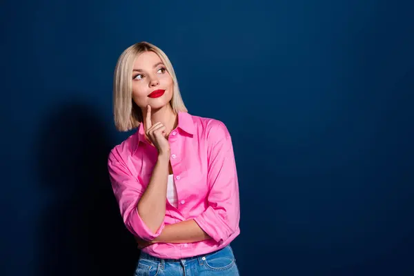Photo portrait of attractive young woman touch chin look minded empty space wear trendy pink clothes isolated on dark blue color background.