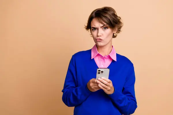 Portrait of minded doubtful person raise eyebrow hold smart phone distrust empty space isolated on beige color background.