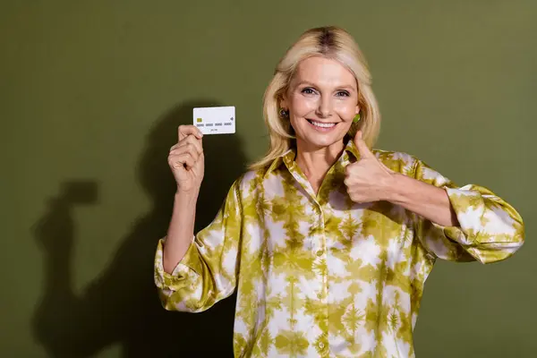 金髪成熟した年齢の写真 笑顔の祖母は カーキ色の背景に隔離された新しいエコード親指のレートバンクカードを促進 — ストック写真