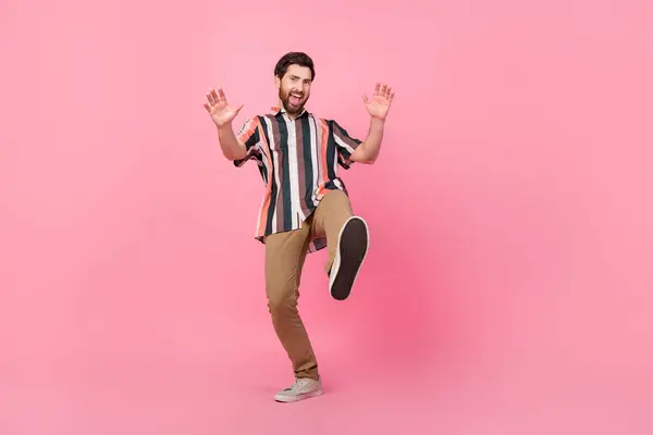 ピンク色の背景に孤立した彼の新しいスニーカーを示すあなたに向かってストライプのシャツのステップでエネルギッシュな若者のフルボディ写真 — ストック写真