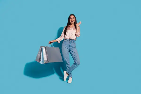 stock image Full size photo of speechless woman dressed silk shirt holding shopping bags raising palm up staring isolated on blue color background.