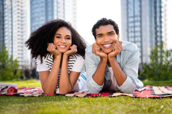 Photo of two positive nice people lying comfy blanket lawn toothy smile spend free time fresh air outside.