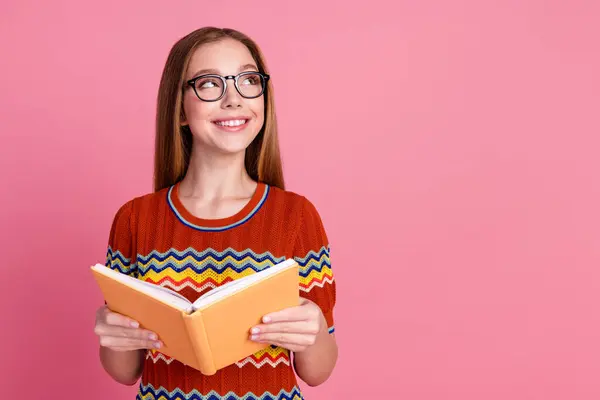 Photo of smart diligent girl hold opened book look empty space brainstorming isolated on pink color background.