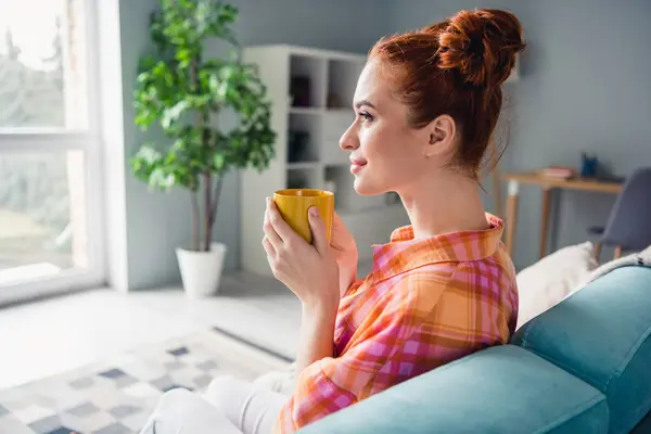 坐在沙发上的漂亮而积极的女士的肖像在室内保持新鲜的咖啡杯的灵感 — 图库照片