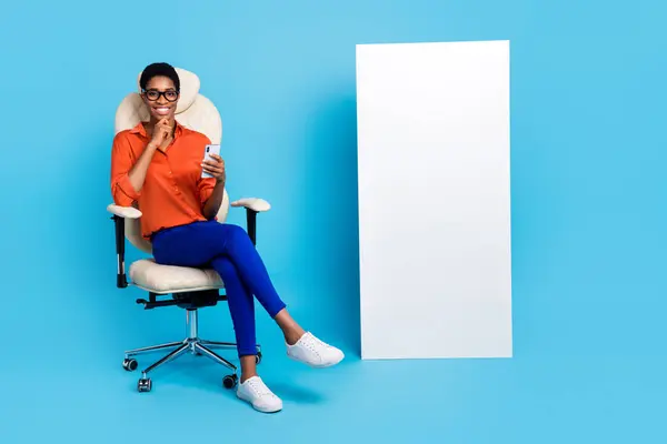 Photo of lady sit chair hold telephone finger chin blank space wall wear specs brown shirt isolated blue color background.