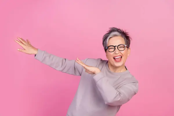 欢快喜庆的女性退休人员欢庆胜利的照片 她在粉色背景下孤身一人跳着胜利之舞 — 图库照片
