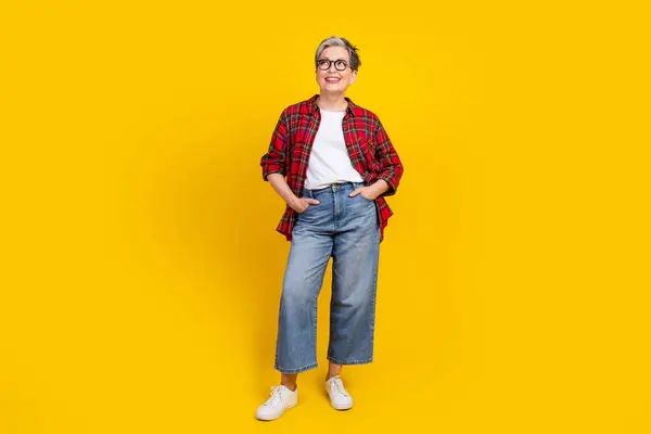 Full body portrait of creative minded lady put arms pockets look empty space isolated on yellow color background.