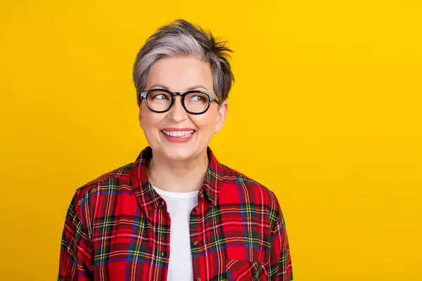 Photo of positive minded lady beaming smile look interested empty space isolated on yellow color background.