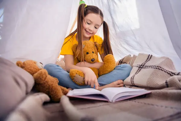 可爱的小女孩坐在地板帐篷上的照片肖像读童话般的玩具穿着时髦的黄色衣服幼儿园的内部 — 图库照片