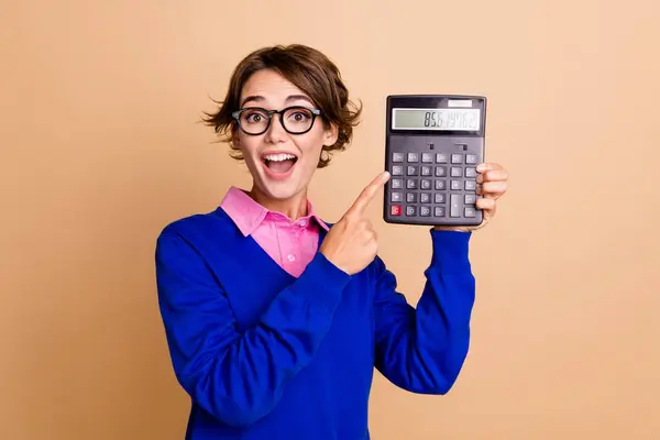 可爱的年轻女士点兴奋的计算器穿着与米色背景相隔离的时髦蓝色衣服的照片肖像 — 图库照片