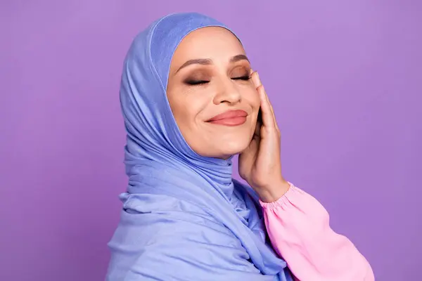豪華な女性のプロフィール写真は 紫色の背景に隔離された青いアラブのヘッドラップを着用することを構成します — ストック写真