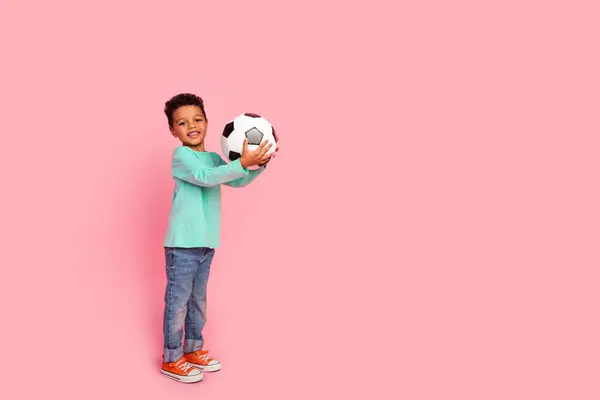 かわいい小さな男の子の遊びのフットボールのフルボディ写真は ピンク色の背景に隔離されたトレンディなアクアマリン服を着用ボールを保持します — ストック写真