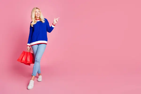 美しい女性のホールドバッグのフルサイズの写真は ピンク色の背景に隔離された青いセーターを着用指の空スペースを示しています — ストック写真