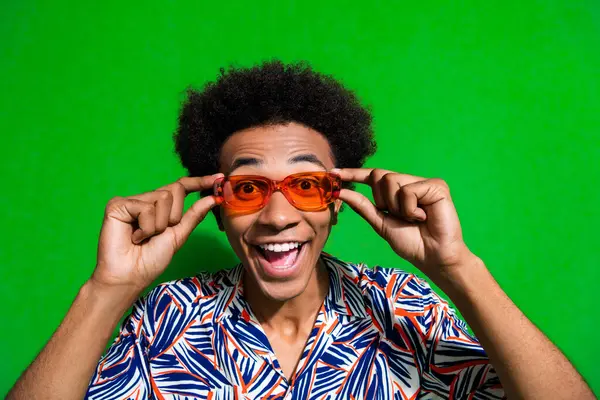 Photo of funky excited man dressed print shirt arms hands eyewear smiling open mouth isolated green color background.
