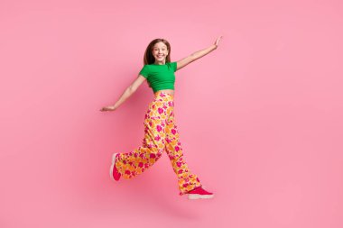 Full length photo of lovely pretty positive girl wear bright clothes fly air open hands isolated on pink color background. clipart