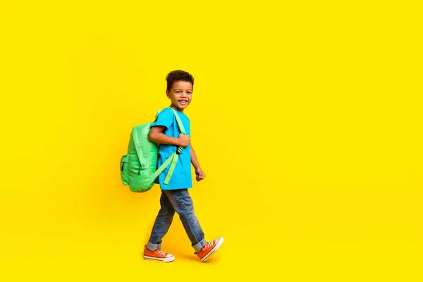 男孩穿着休闲蓝T恤 头戴背包上学的全副照片 空旷的空间 背景是鲜亮的黄色 — 图库照片